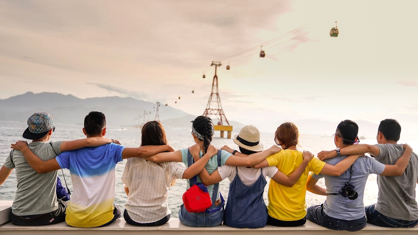 A diverse group of people sitting together with arms linked, representing community and inclusion