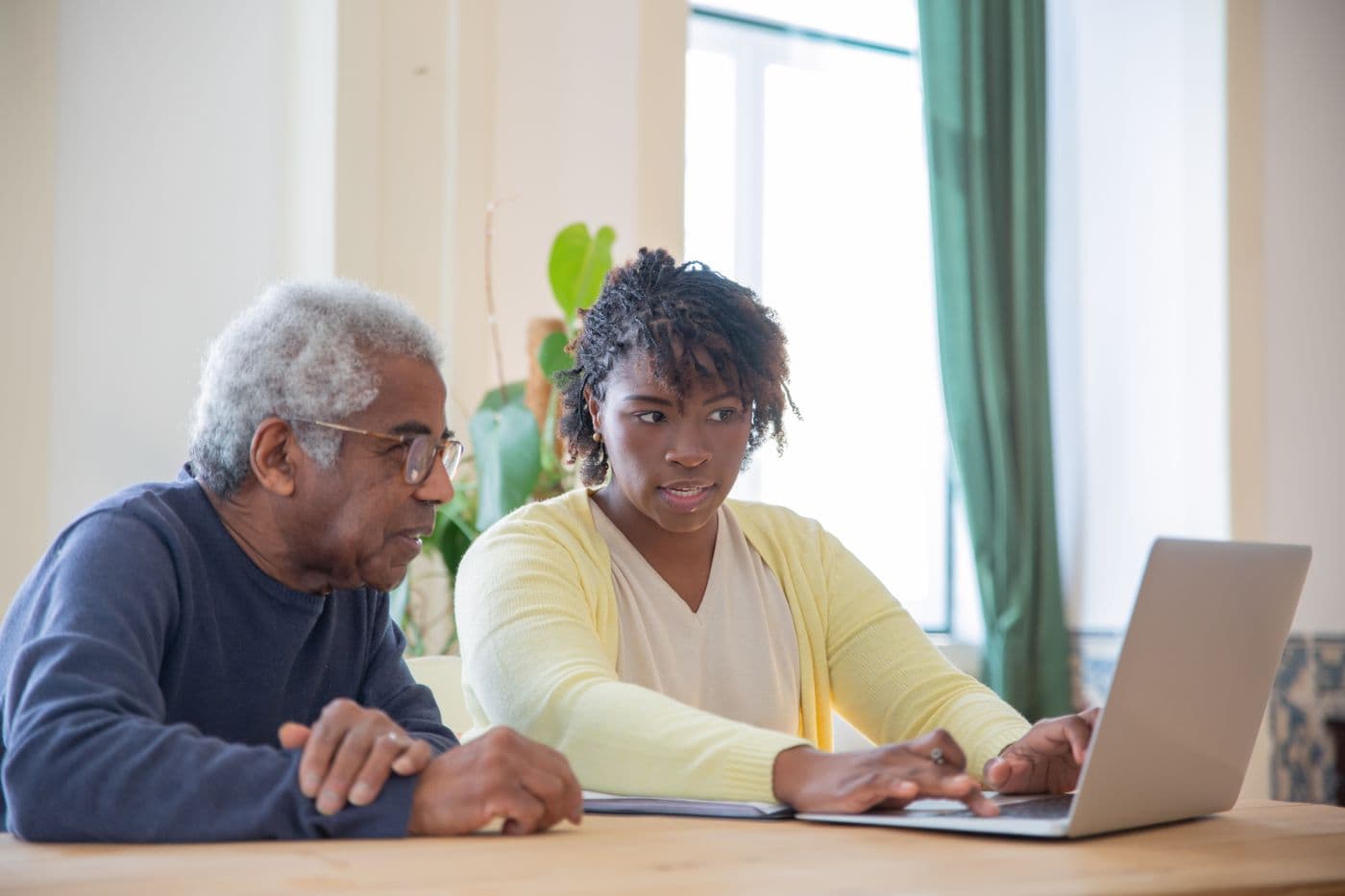 A partner supporting an older person with visual difficulty during a learning session, representing collaboration and shared resources